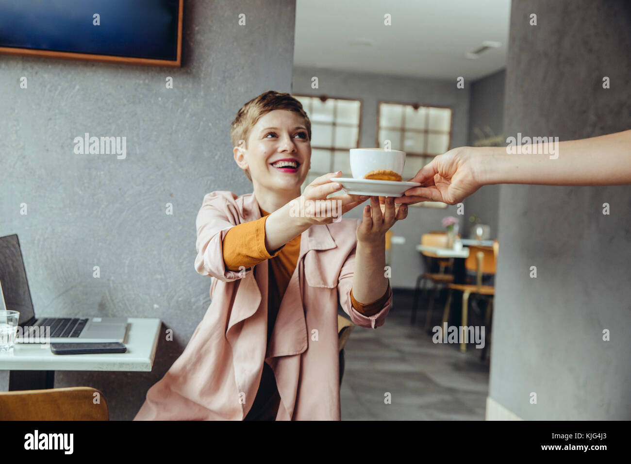 Frau im Cafe mit Laptop empfangen einer Tasse Kaffee Stockfoto