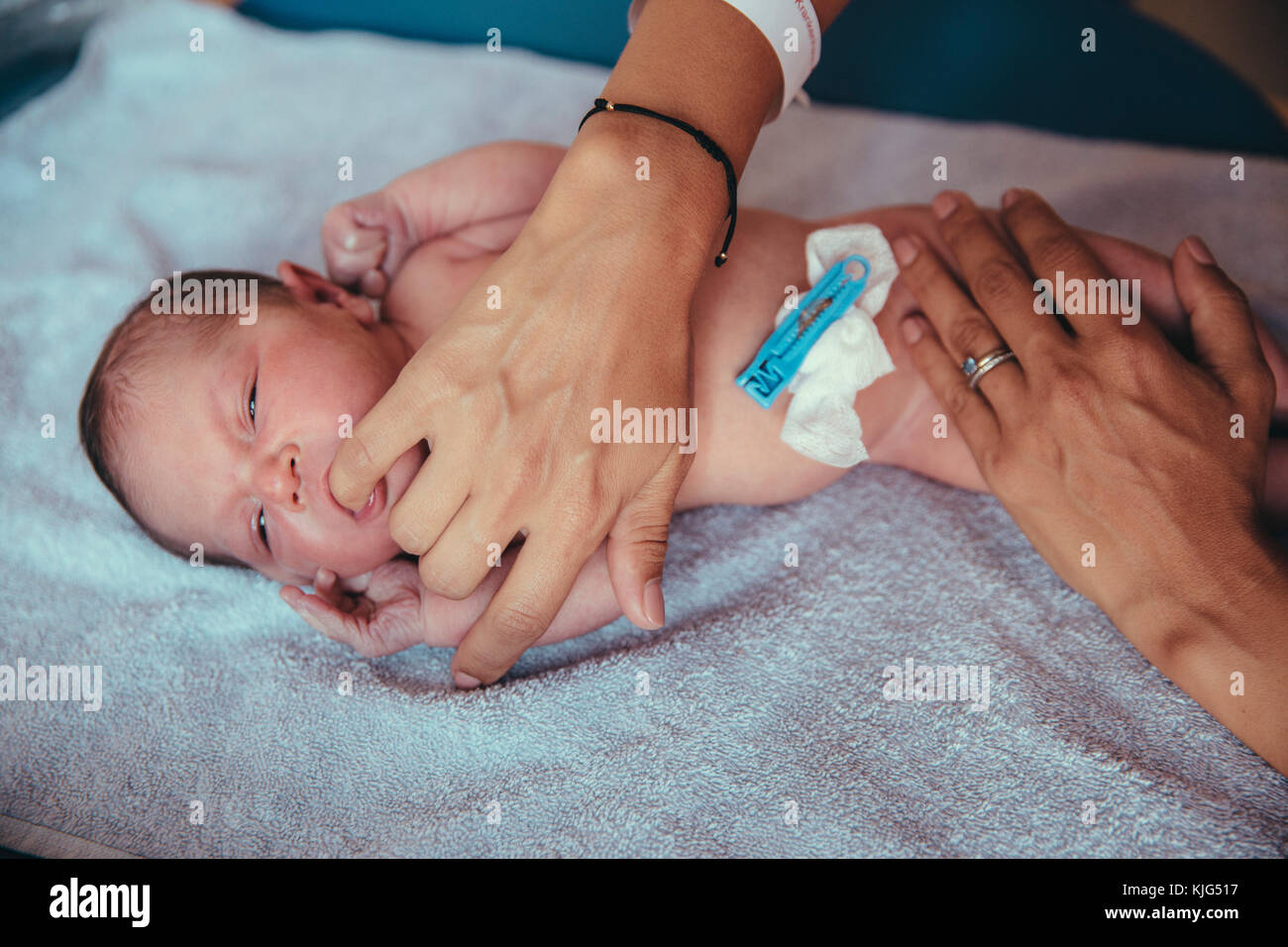 Neugeborene Mädchen liegt auf dem Handtuch saugen bei der Mutter Finger Stockfoto