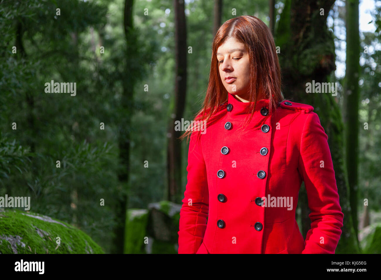 Junge Frau traurig alleine auf den Waldweg das Tragen der roten langen Mantel oder Jacke. Mädchen geht auf Spaziergang in den Wäldern des Naturparks im Herbst, Stockfoto