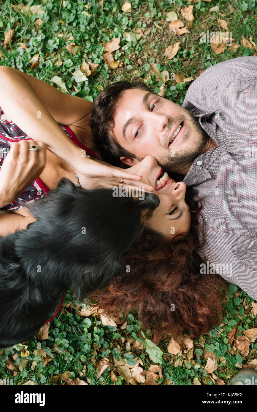 Glückliches Paar in der Liebe mit Hund liegend auf der Wiese Stockfoto