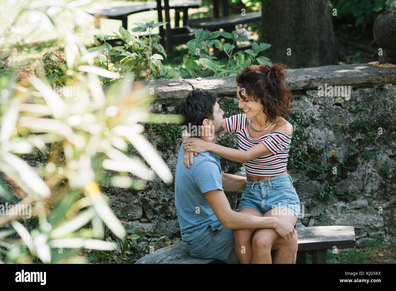 Paar in Liebe umarmen auf der Werkbank in einem Park Stockfoto