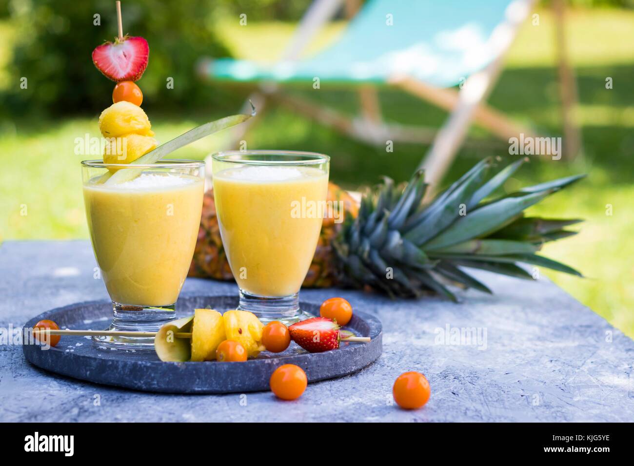 Zwei Gläser tropical Smoothie mit Ananas, Mango, Kokosmilch und Kokosraspeln Stockfoto