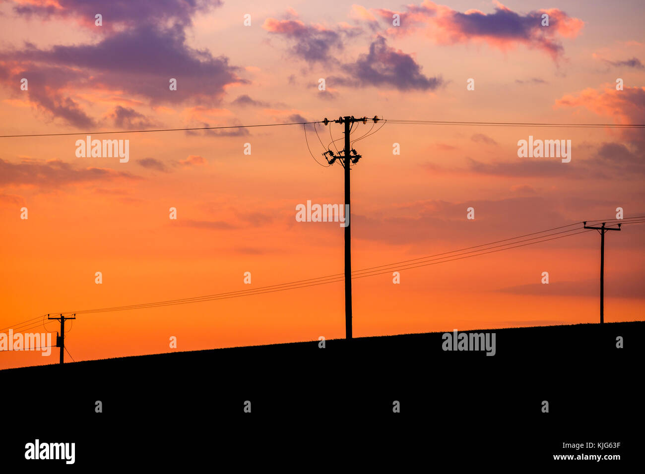 Powerlines und Telefon Kabel gegen ein Sonnenuntergang in Ayr, Schottland, Großbritannien. Stockfoto