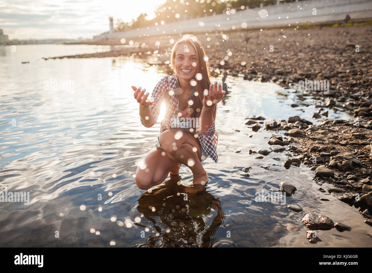 Glückliche junge Frau entsprechende/r in einem Fluss bei Sonnenuntergang Stockfoto