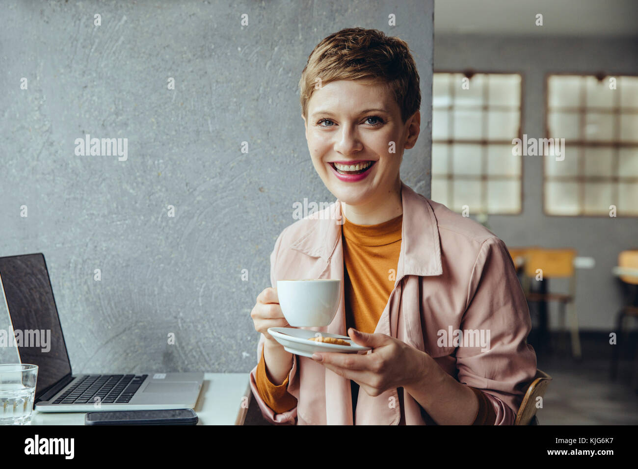 Porträt der lächelnde Frau im Cafe mit Laptop und Tasse Kaffee Stockfoto