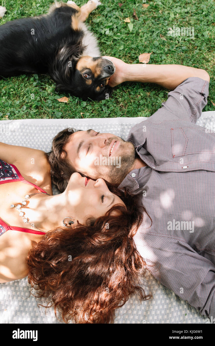 Verliebtes Paar mit Hund liegend auf einer Decke Stockfoto