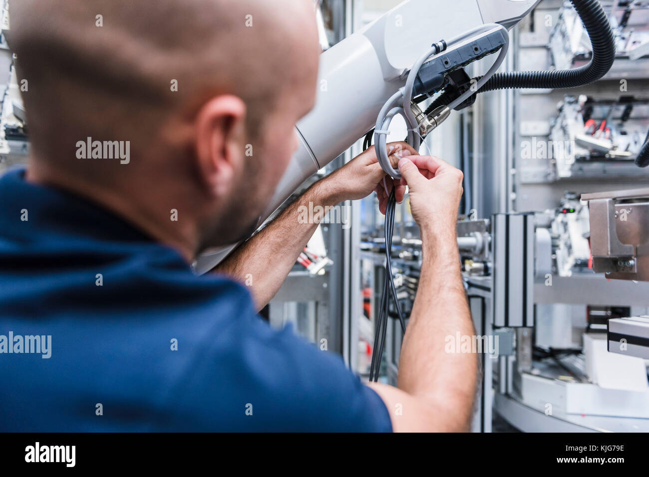 Mann an Industrieroboter in der modernen Fabrik arbeiten Stockfoto