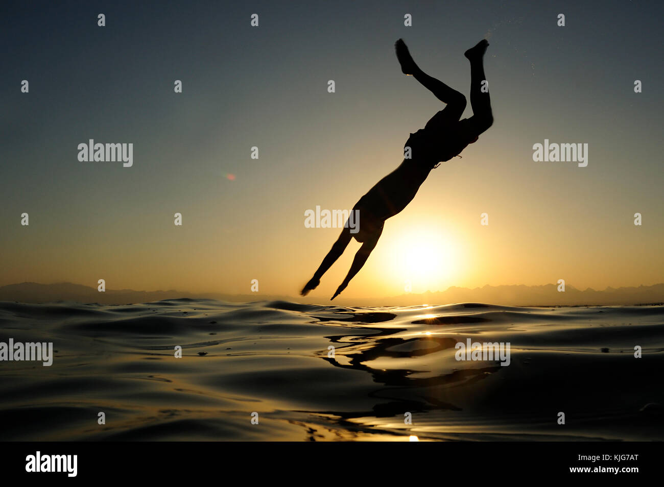 Mann springt in das Meer bei Sonnenuntergang Stockfoto