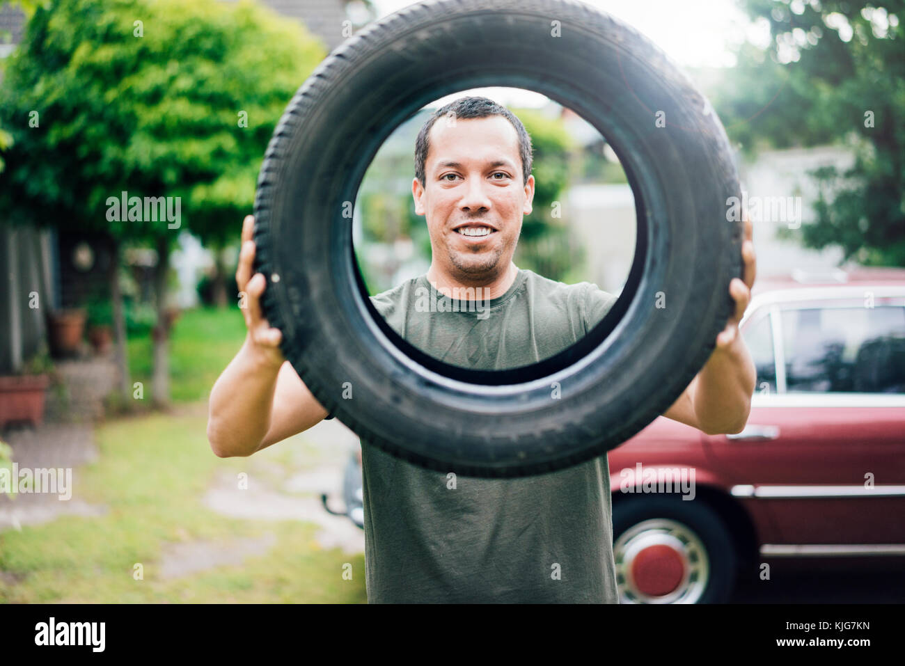 Portrait von lächelnden Mann mit Auto Reifen Stockfoto