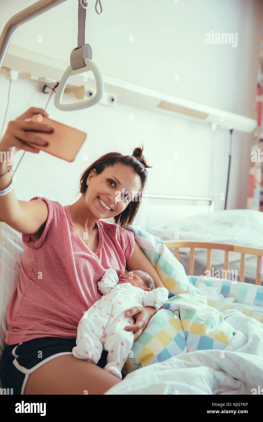 Mutter ein Selbstporträt mit ihrem Neugeborenen Baby im Krankenhausbett Stockfoto