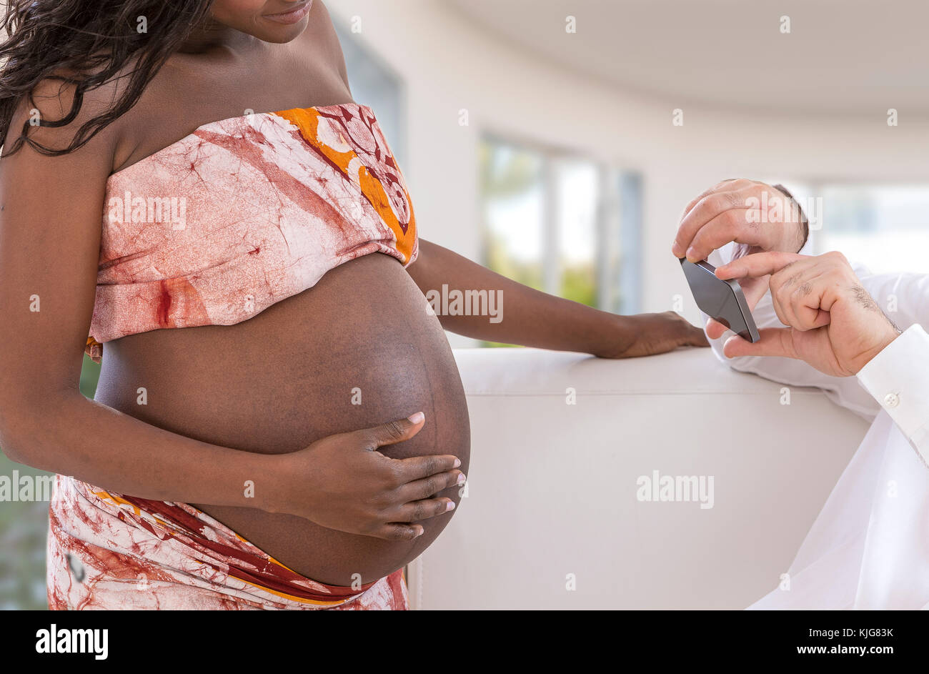 Schöner Mann nimmt Fotos mit Smartphone von Jungen glücklich Schwangere Frau Wohnzimmer Stockfoto