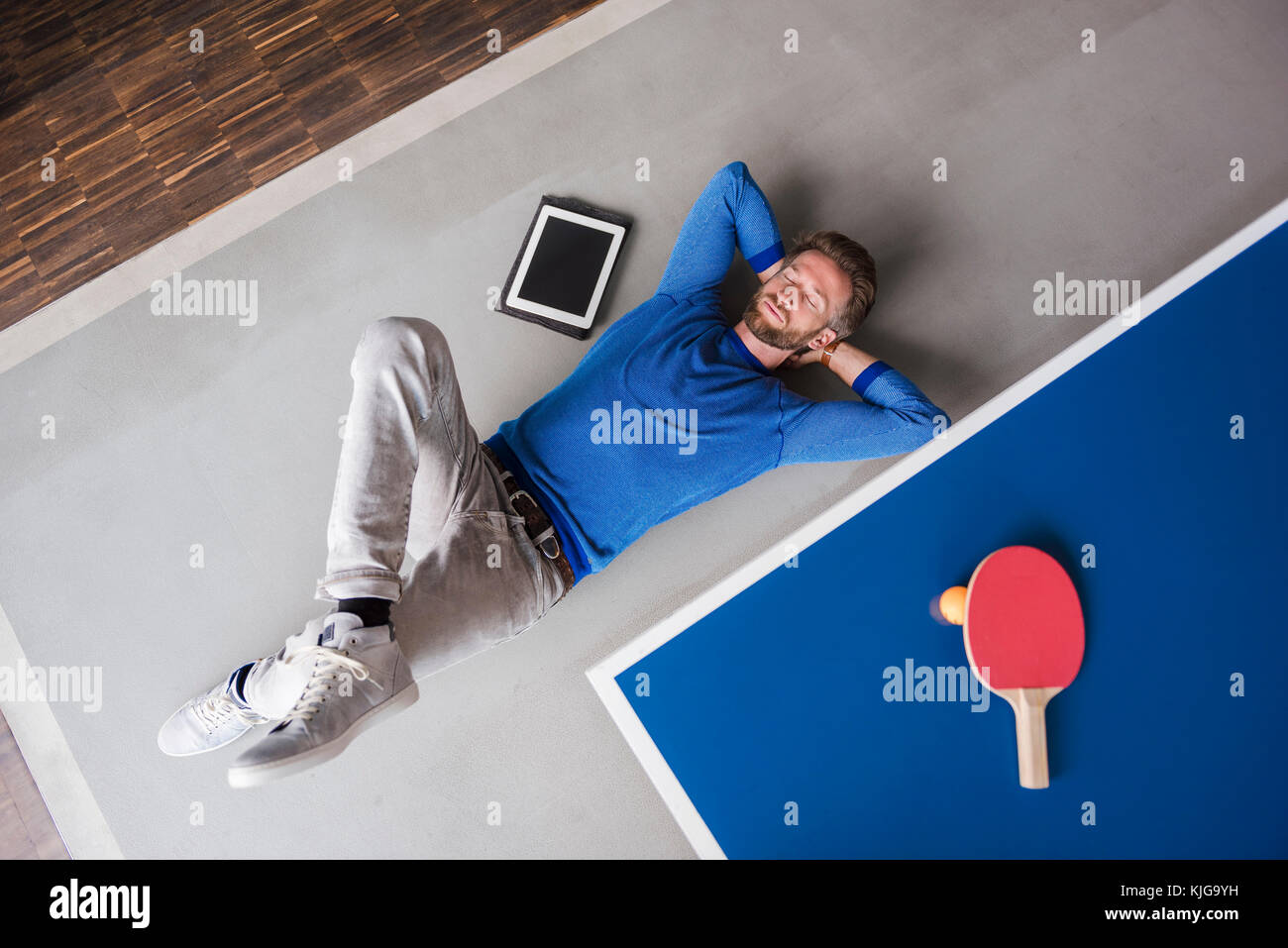 Mann auf dem Boden liegend mit Tablette im Pausenraum des modernen Büro Stockfoto
