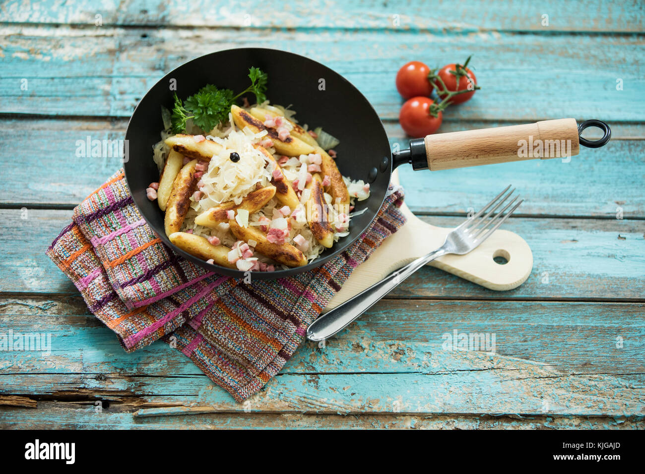 Bratpfanne von Finger-förmige Kartoffel Knödel mit Sauerkraut und Speck auf Tuch und Holzbrett Stockfoto