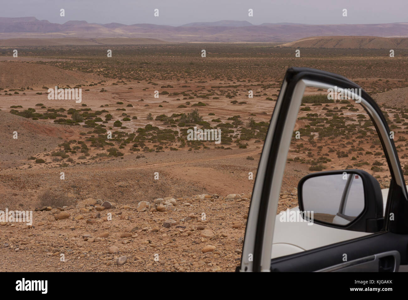 Öffnen Fahrerseite Auto vor der Tür über die Morocan Wüste suchen mit Bergen im Hintergrund Stockfoto