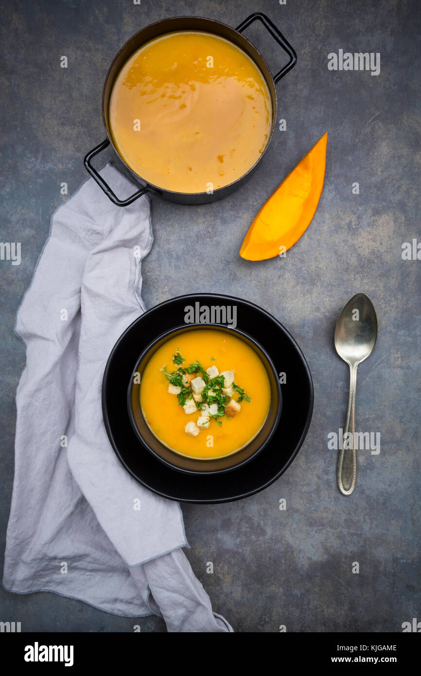 Suppe Teller der cremige Kürbissuppe mit Croutons und Petersilie und Kürbissuppe im Kochtopf Stockfoto