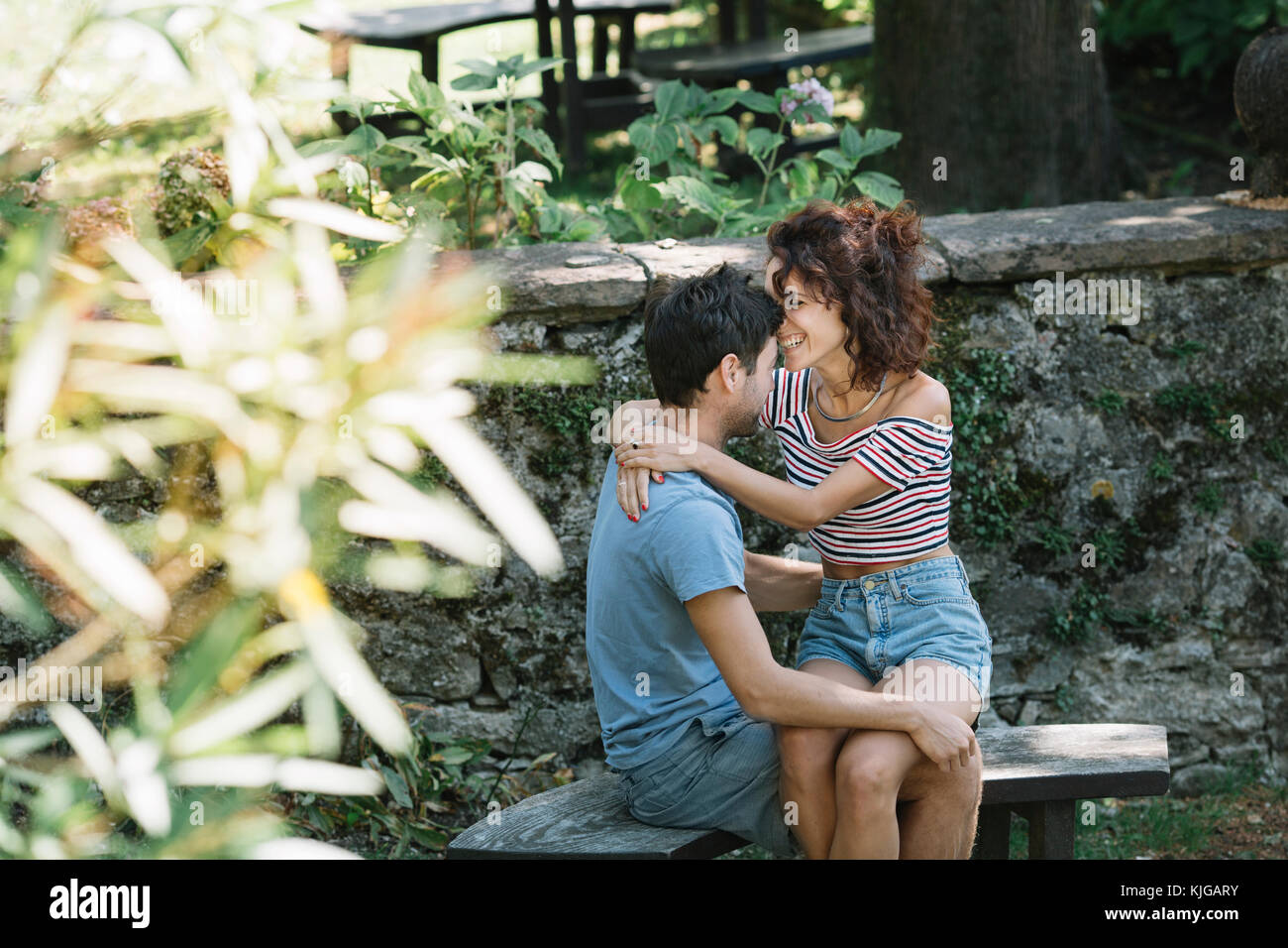 Paar in Liebe umarmen auf der Werkbank in einem Park Stockfoto