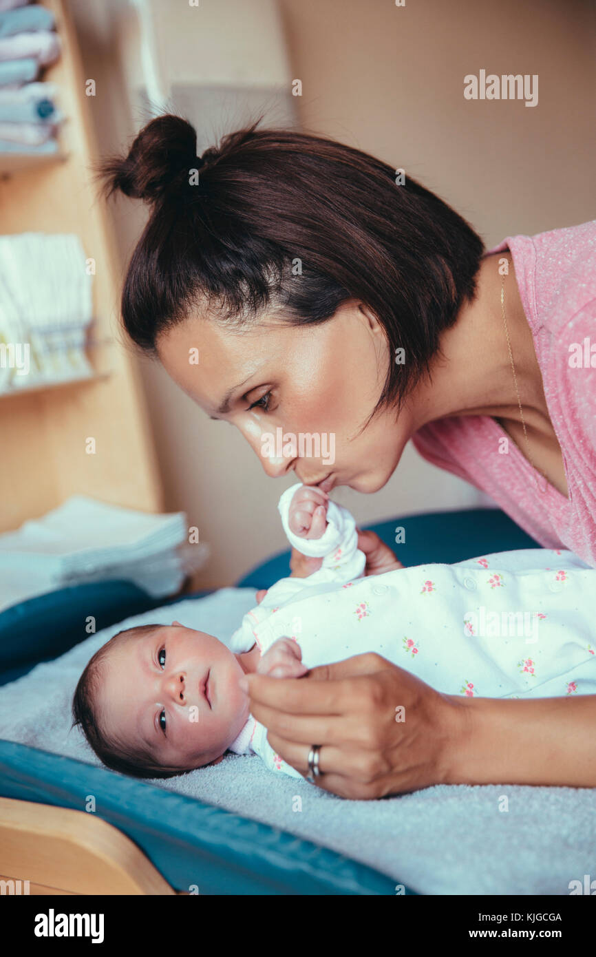 Mutter küssen Hand ihr neugeborenes Baby Mädchen im Krankenhaus Zimmer Stockfoto