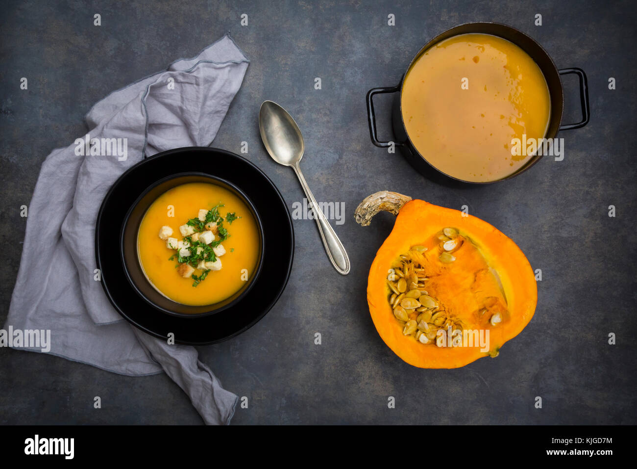 Suppe Teller der cremige Kürbissuppe mit Croutons und Petersilie, die Hälfte der Kürbis und Kürbis Suppe im Topf Stockfoto