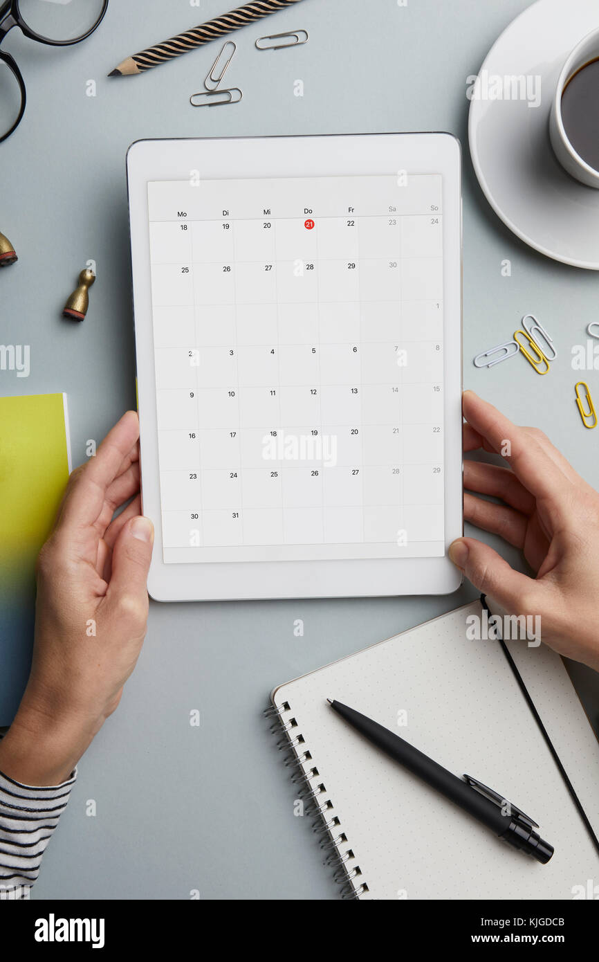 Blick von oben auf die Frau mit Tablet mit dem Kalender auf dem Schreibtisch Stockfoto