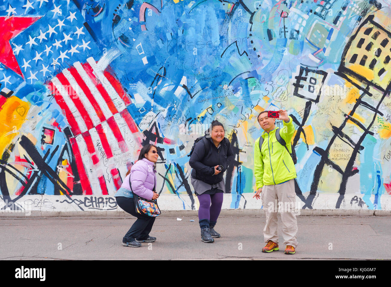 Berliner Mauer, Touristen posieren für ein selfie vor einem bunten Abschnitt der Berliner Mauer an der East Side Gallery in Friedrichshain, Berlin, Deutschland Stockfoto