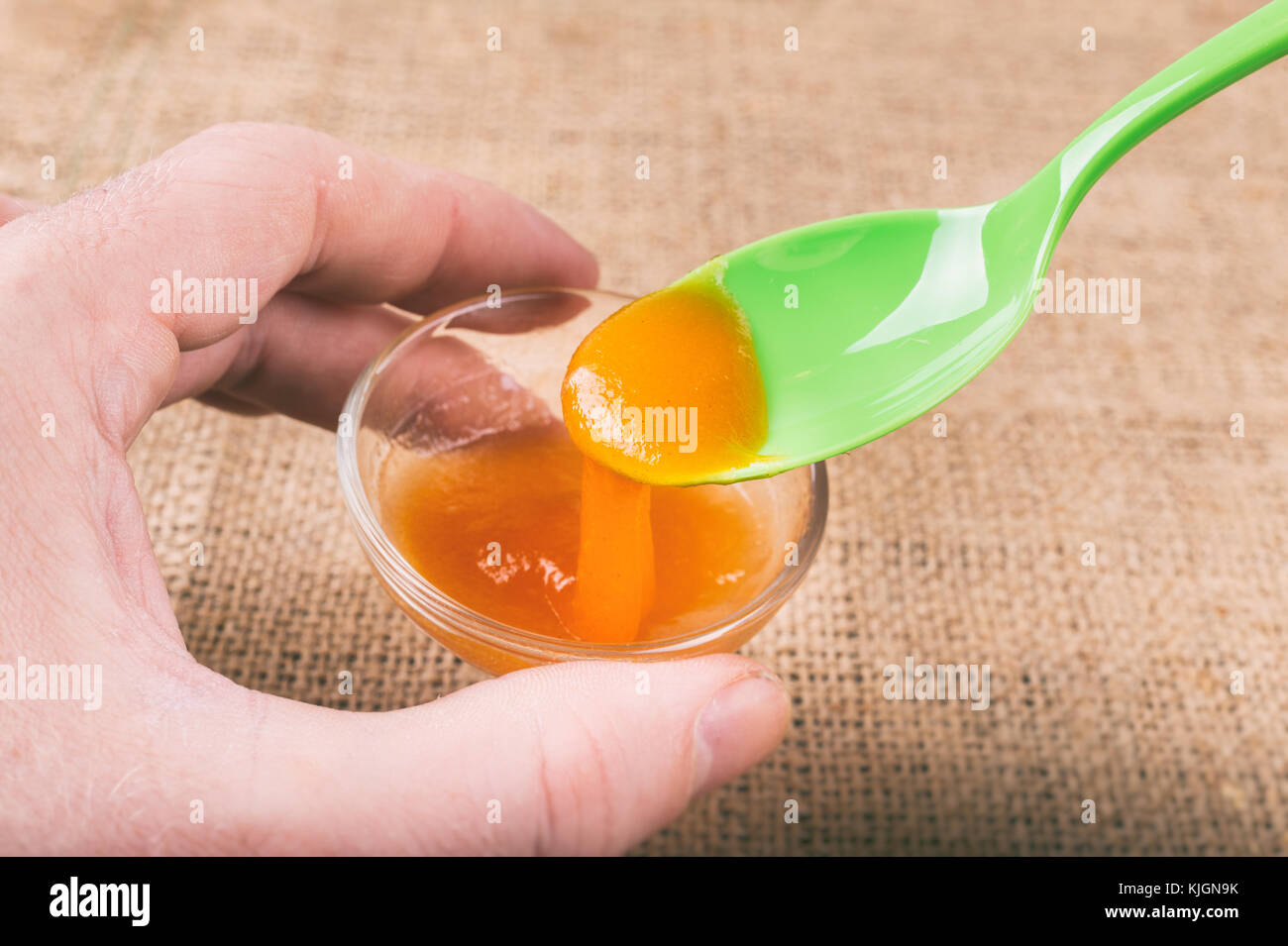 Hand mit einem Glas orange Jelly aus Psyllium Schleim Stockfoto