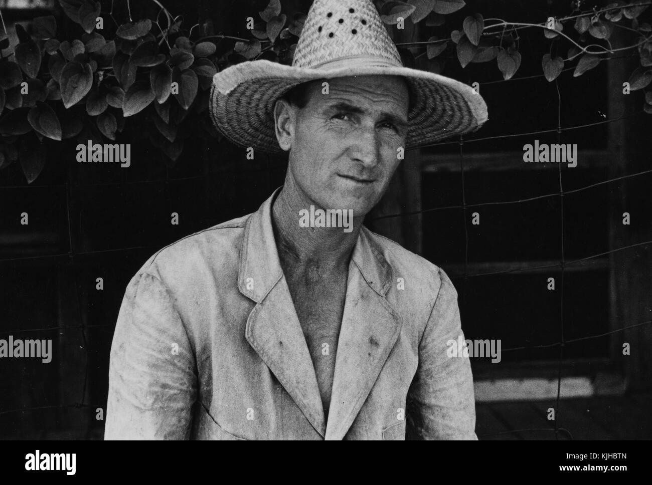 Schwarz-weiß-Foto von Jaspar Lancaster, einem Rehabilitationskunden, der eine Jacke und einen großen Strohhut trägt, von Ben Shahn, einem in Litauen geborenen amerikanischen Künstler, der für seine Arbeit für die Farm Security Administration bekannt ist, die die Auswirkungen der Großen Depression im Mississippi County, Arkansas, 1935 dokumentiert. Aus der New York Public Library. Stockfoto