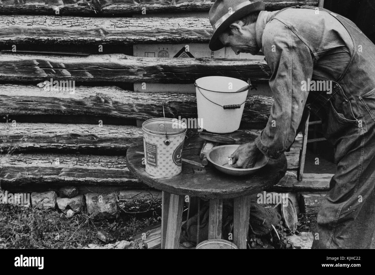 Schwarz-weiß-Fotografie eines Mannes, der seine Hände in einer provisorischen Waschstation in einem Besetzerlager wäscht, von Ben Shahn, gebürtiger Litauer, US-amerikanischer Künstler, der für seine Arbeit für die Farm Security Administration bekannt ist, die die Auswirkungen der Großen Depression in Ozarks, Arkansas, 1935 dokumentiert. Aus der New York Public Library. Stockfoto