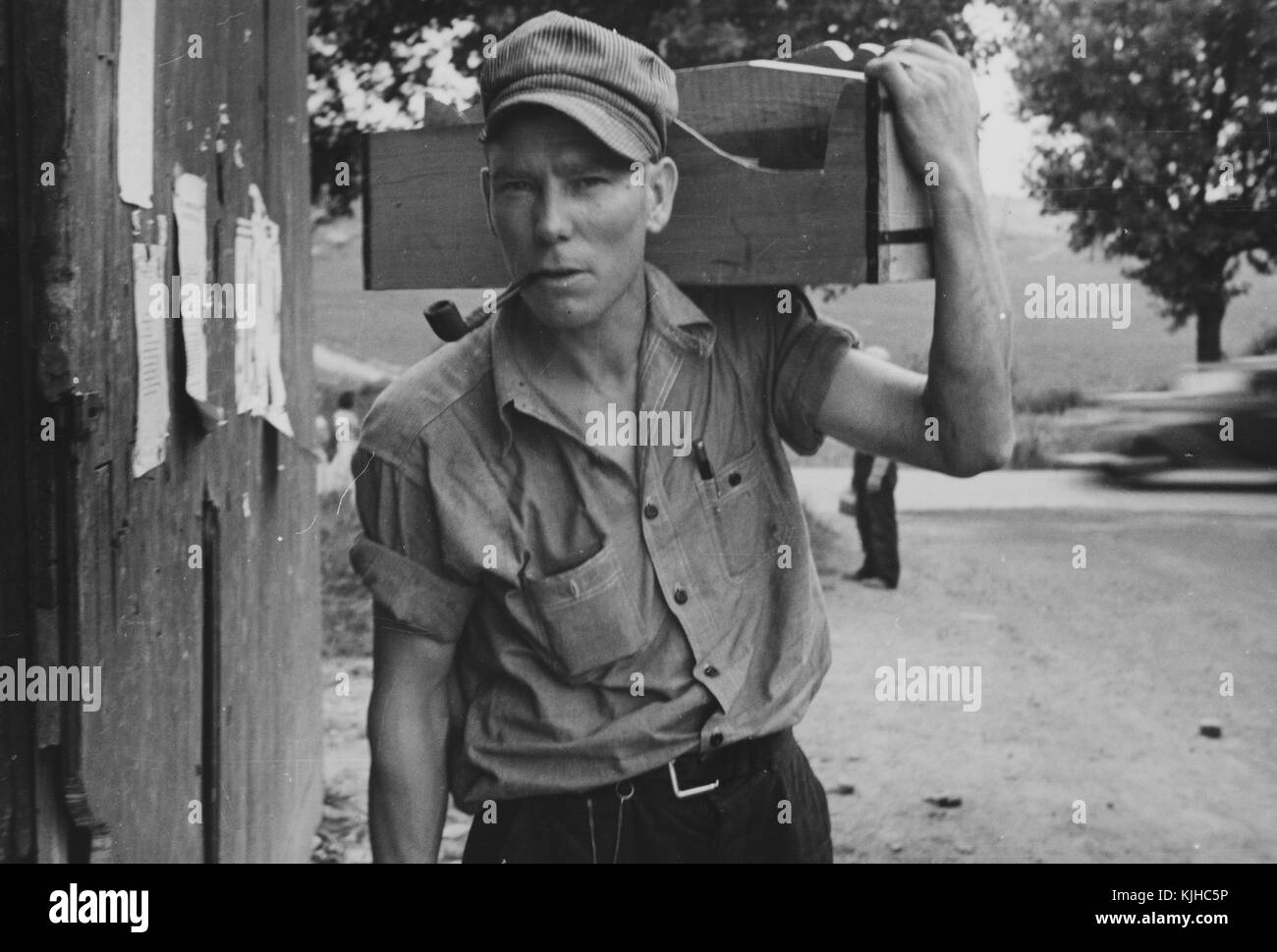 Schwarz-weiß Foto eines Zimmermanns und hielt seinen Toolbox auf seine Schulter, das Rauchen einer Pfeife, von Walker Evans, US-amerikanischer Fotograf für seine Arbeit bekannt für die Farm Security Administration dokumentieren die Auswirkungen der Großen Depression, als Teil eines befristeten fotografische Kampagne für die Umsiedlung der Verwaltung, Westmoreland County, Pennsylvania, 1935 von der New York Public Library. Stockfoto