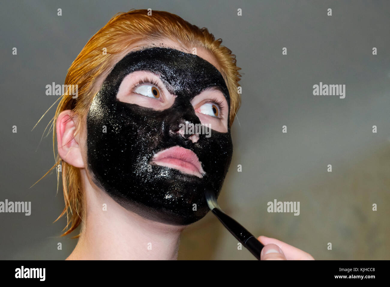Mädchen in einem kosmetischen schwarze Maske. reinigende Maske von Aspirin  und Aktivkohle. Schwarz kosmetische Gesichtsmaske Stockfotografie - Alamy