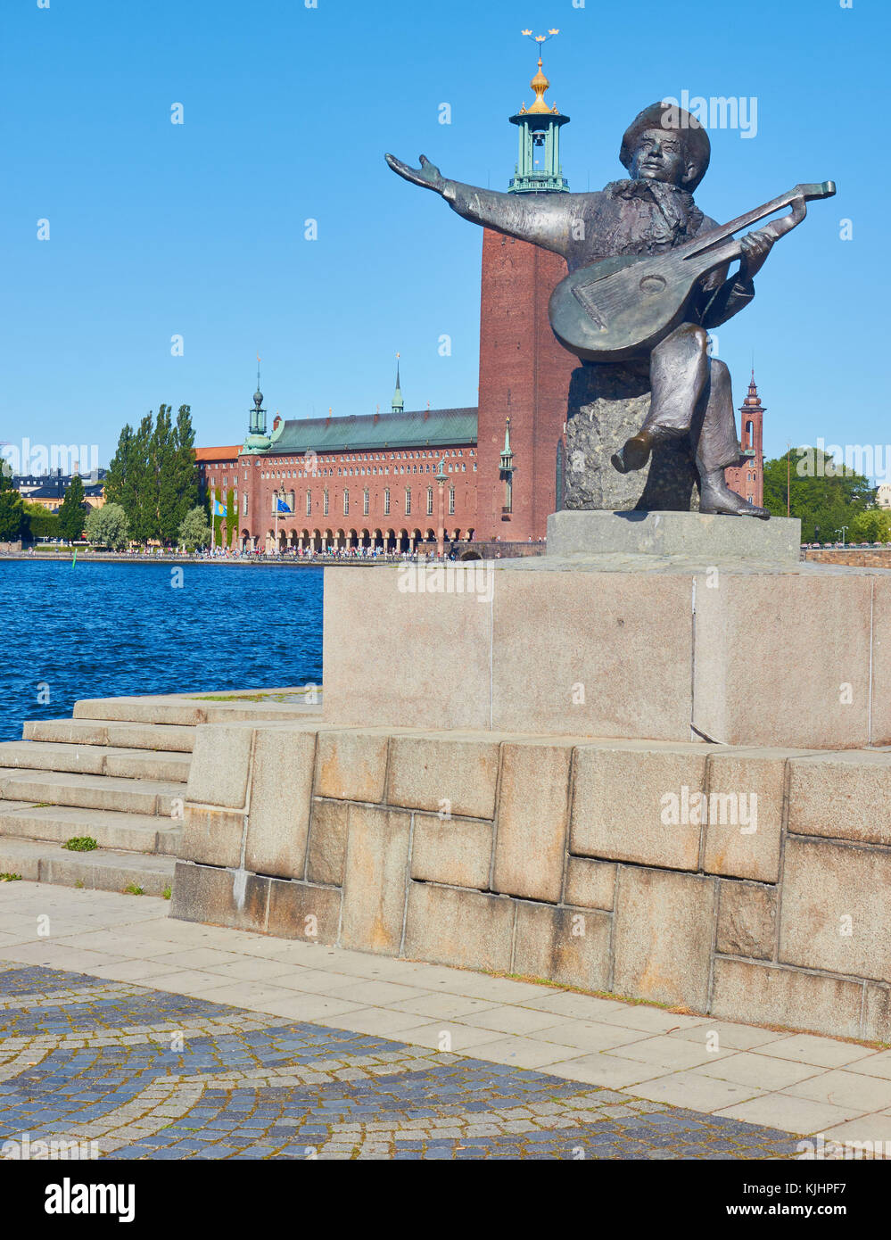Statue von Evert Taube vor allem Troubadour der Schwedischen Ballade Tradition mit Stadshuset (Rathaus) im Hintergrund, Riddarholmen, Stockholm, Schweden Stockfoto