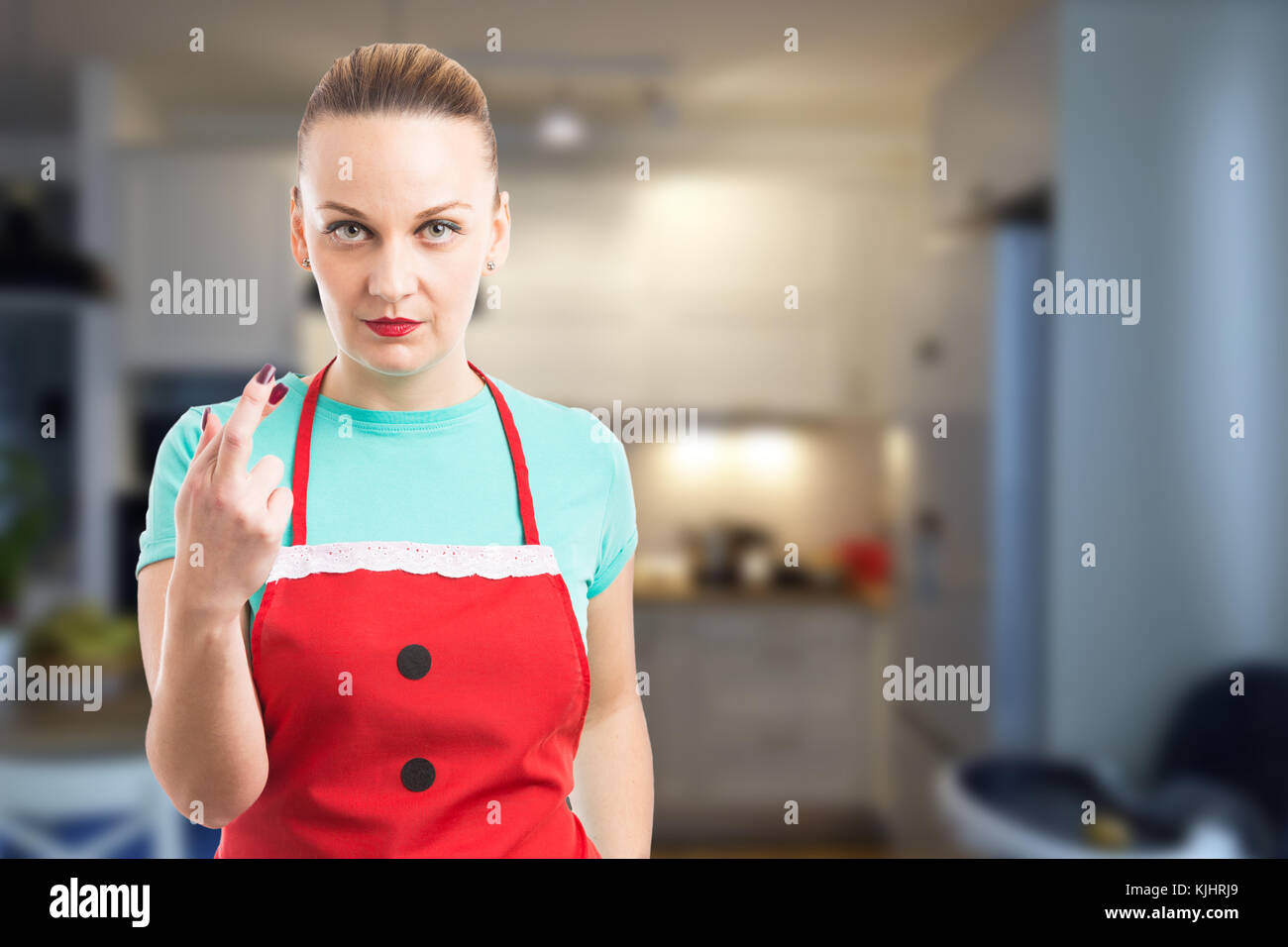 Hausmädchen oder eine Haushälterin, die Pech Geste mit gekreuzten Fingern das Tragen der roten Schürze auf Küche Hintergrund Stockfoto