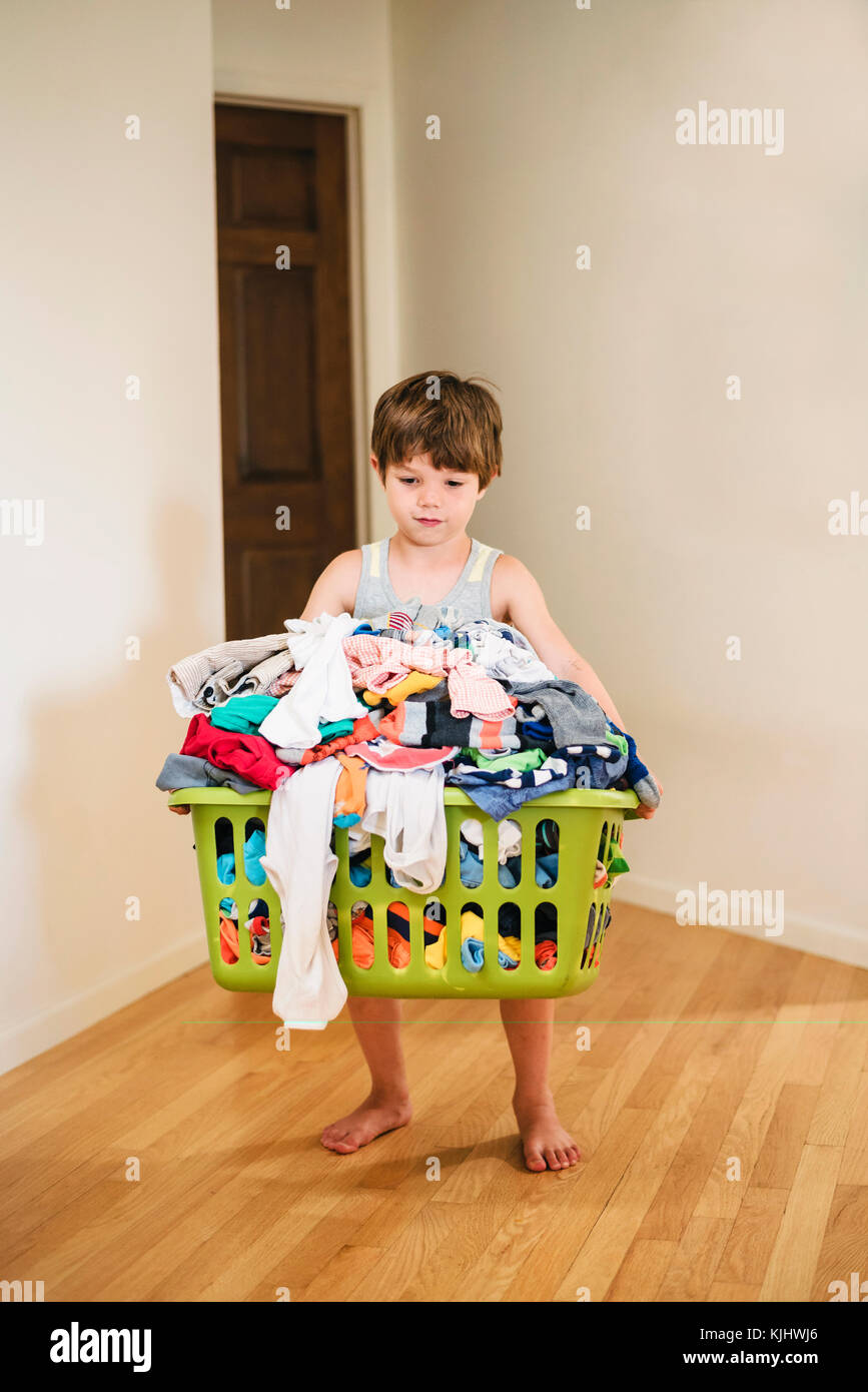 Junge, die Wäsche Korb gefüllt mit Kleidung Stockfoto