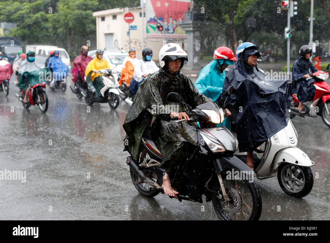 Schwere Monsunregen. Vietnamesische Leute fahren Motorräder auf Saigon Straße. Ho Chi Minh City. Vietnam. Stockfoto