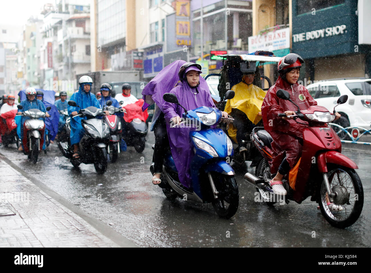 Schwere Monsunregen. Vietnamesische Leute fahren Motorräder auf Saigon Straße. Ho Chi Minh City. Vietnam. Stockfoto