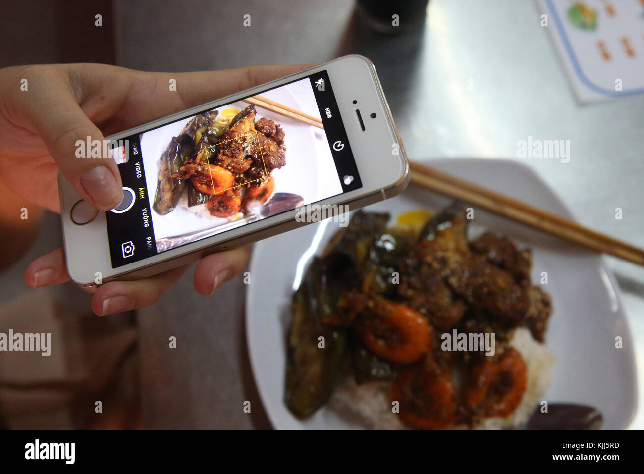 Frau mit ihrem Smartphone ein Bild Ihrer Mahlzeit zu nehmen. Hoi An. Vietnam. Stockfoto