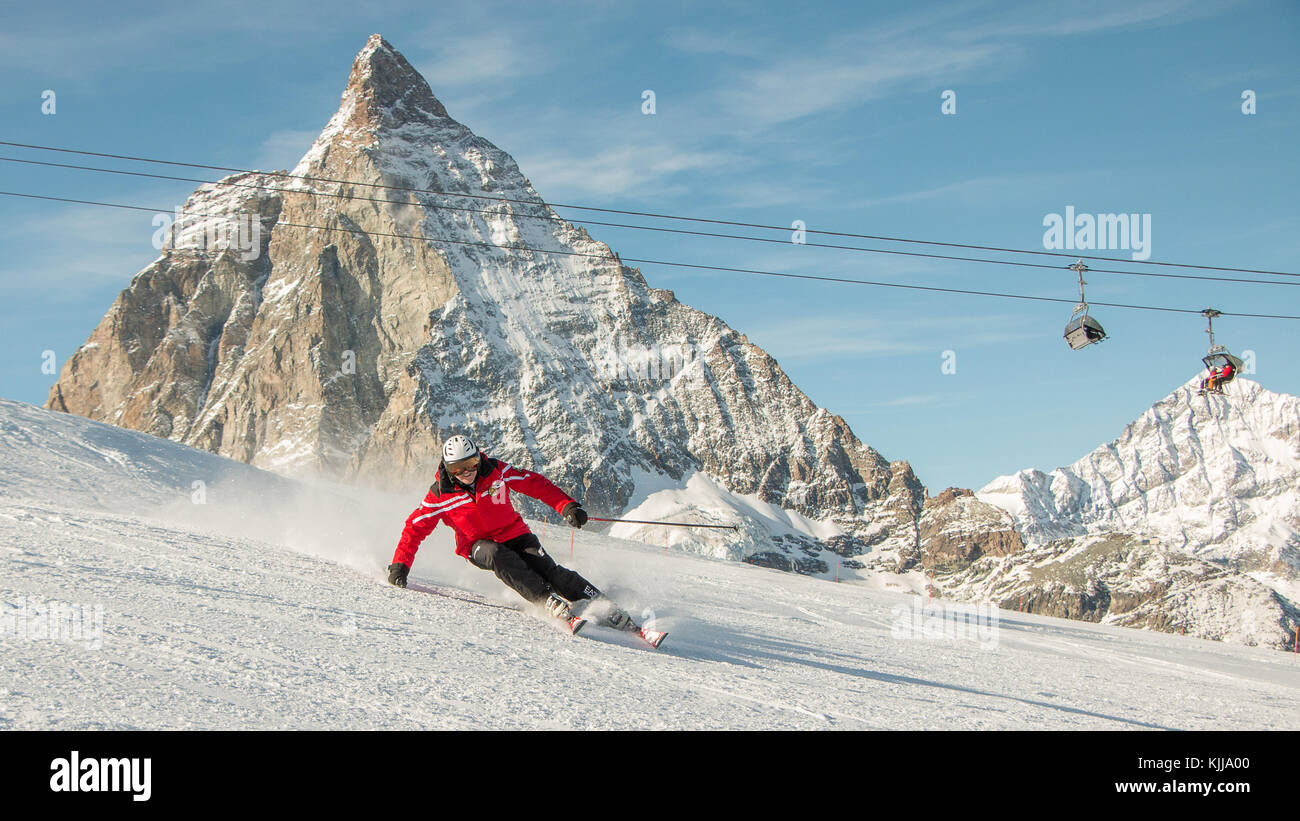 Ein Mann Skilehrer Skifahren vor dem Matterhorn Zermatt Ski Resort der  Schweiz rote Jacke weißen Schnee Ski Helm Sessellift Stockfotografie - Alamy