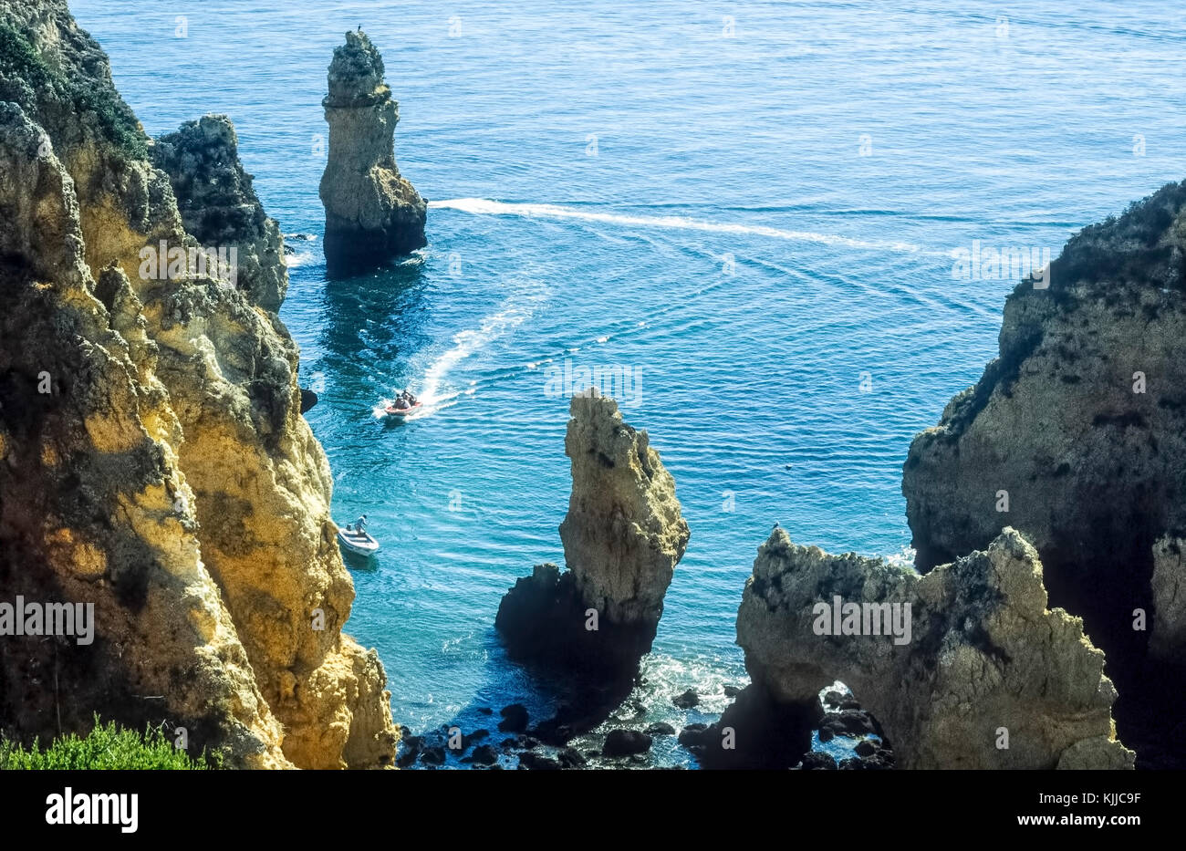 Clifftop Blick auf die Boote segeln durch die markanten Felsformationen an der Küste der Algarve, Portugal. Stockfoto