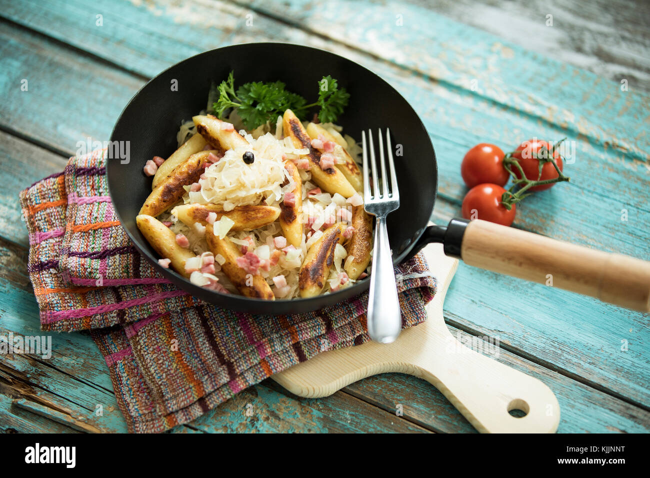 Bratpfanne von Finger-förmige Kartoffel Knödel mit Sauerkraut und Speck auf Tuch und Holzbrett Stockfoto