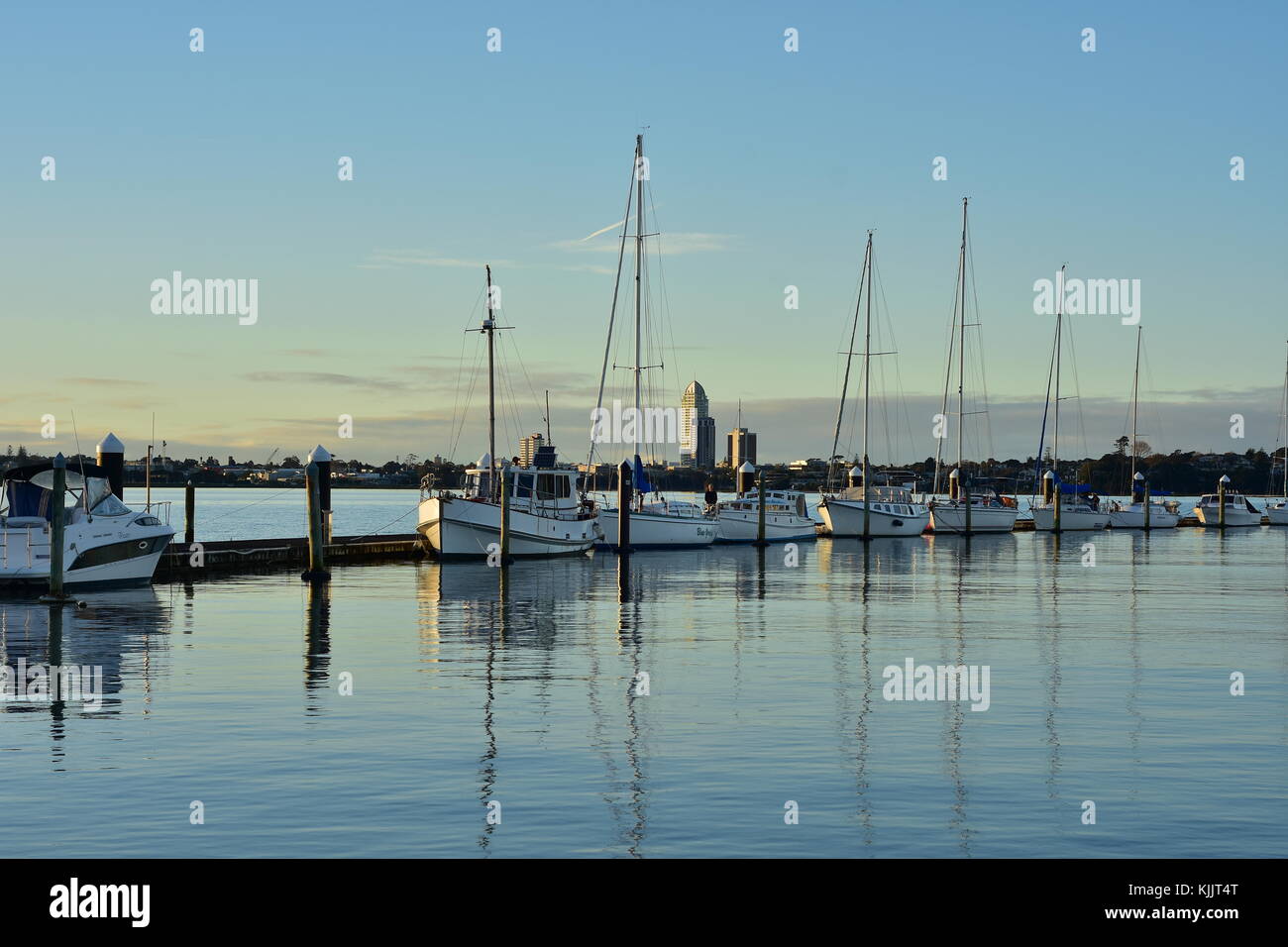 Segel- und Motoryachten günstig entlang der schwimmenden Anlegestelle im Abendlicht. Stockfoto