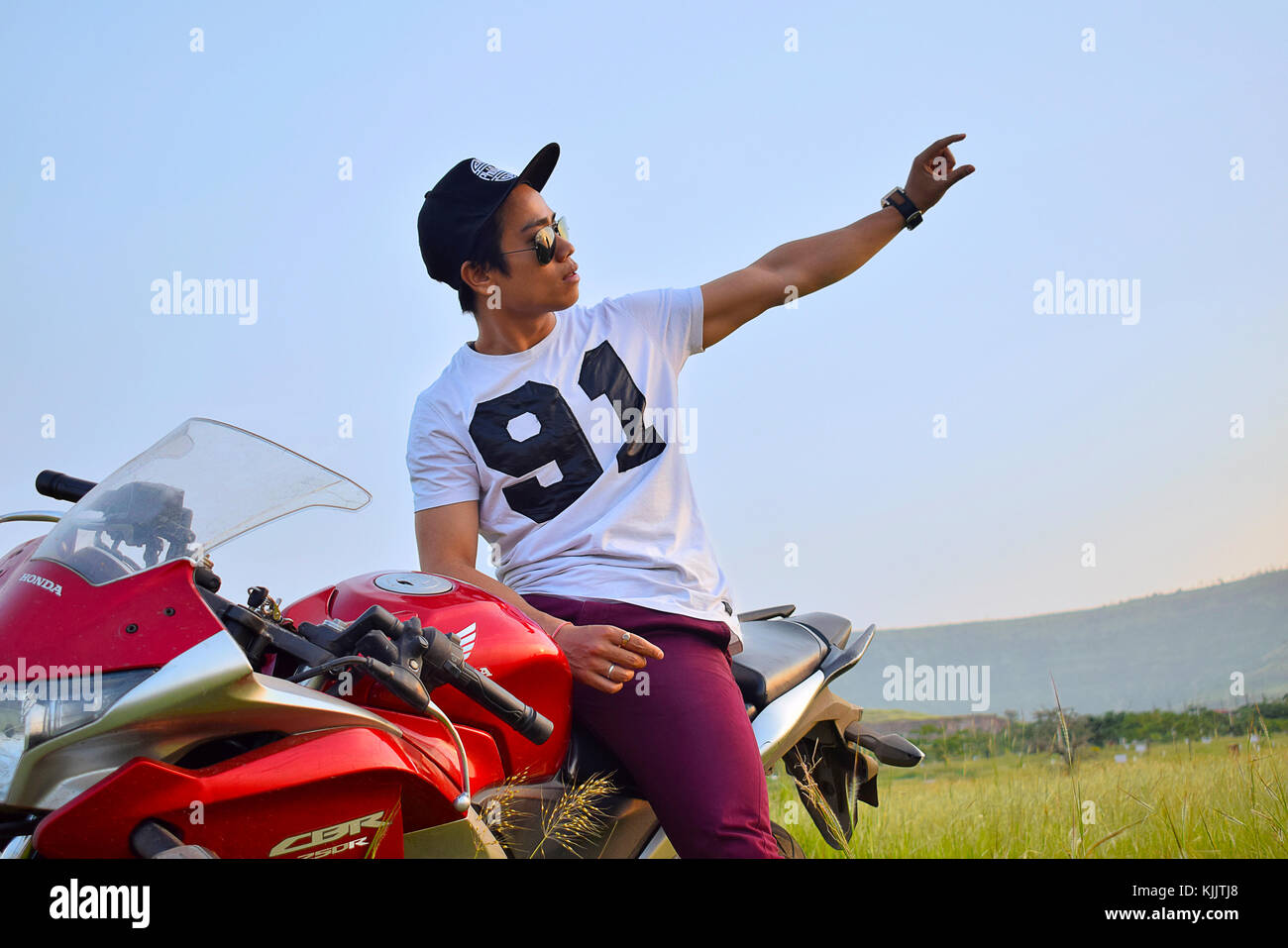 Indischer Junge mit Motorrad und die Berge im Hintergrund. Pune, Maharashtra. Stockfoto