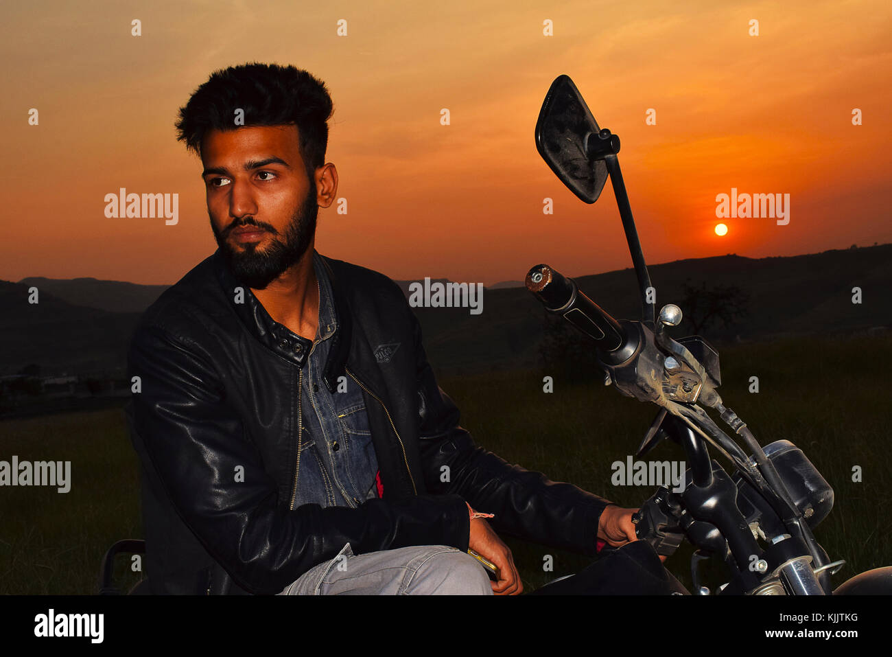 Indischer Junge posiert auf Motorrad in der Nähe von Mountain bei Sonnenuntergang, Pune, Maharashtra. Stockfoto