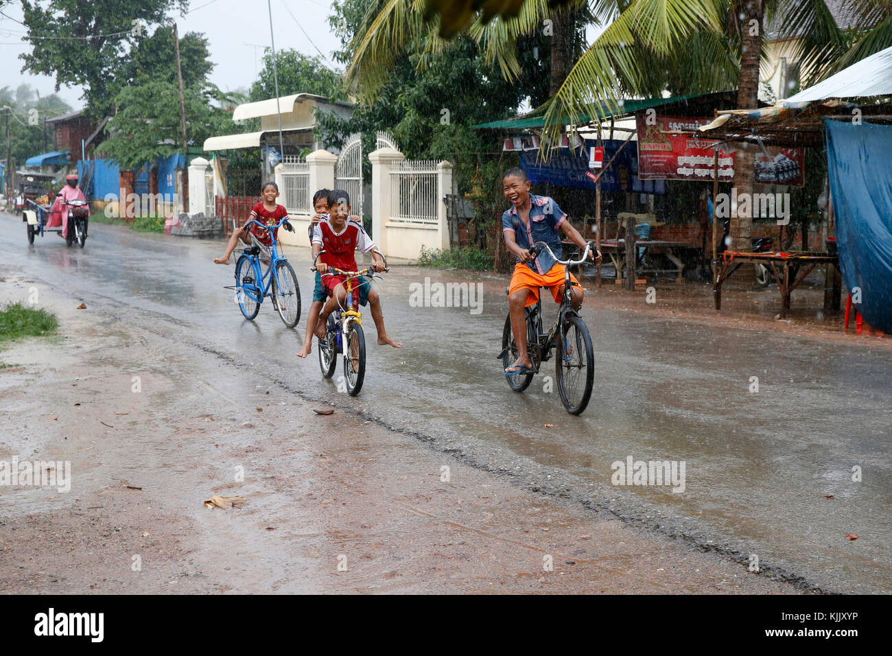 Kinder Radfahren im Regen. Battambang. Kambodscha. Stockfoto