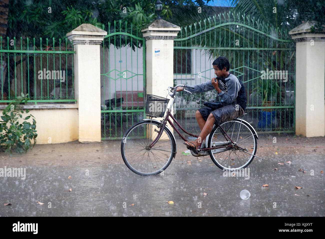 Khmer boy Fahrrad Fahren im Regen. Battambang. Kambodscha. Stockfoto