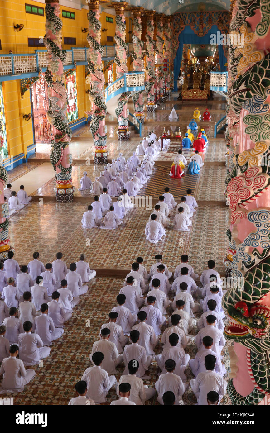 Cao Dai Tempel Heiliger Stuhl. Beten fromme Männer und Frauen, feierliche Mittag Gebet. Thay Ninh. Vietnam. Stockfoto