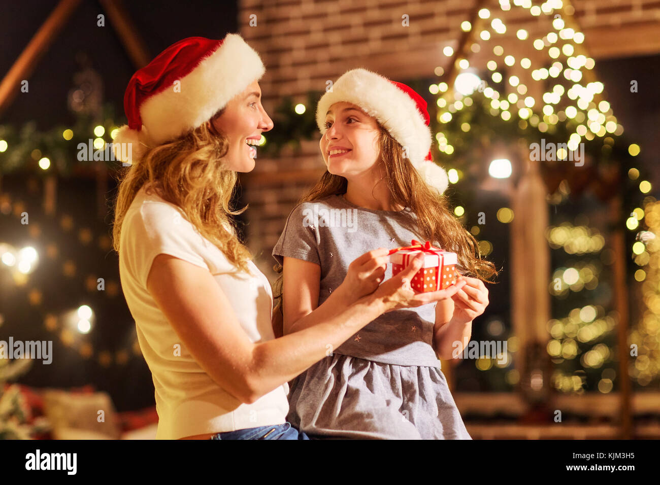 Mutter und Tochter in santa Hüte Geschenke in einem Raum auf Chr Stockfoto