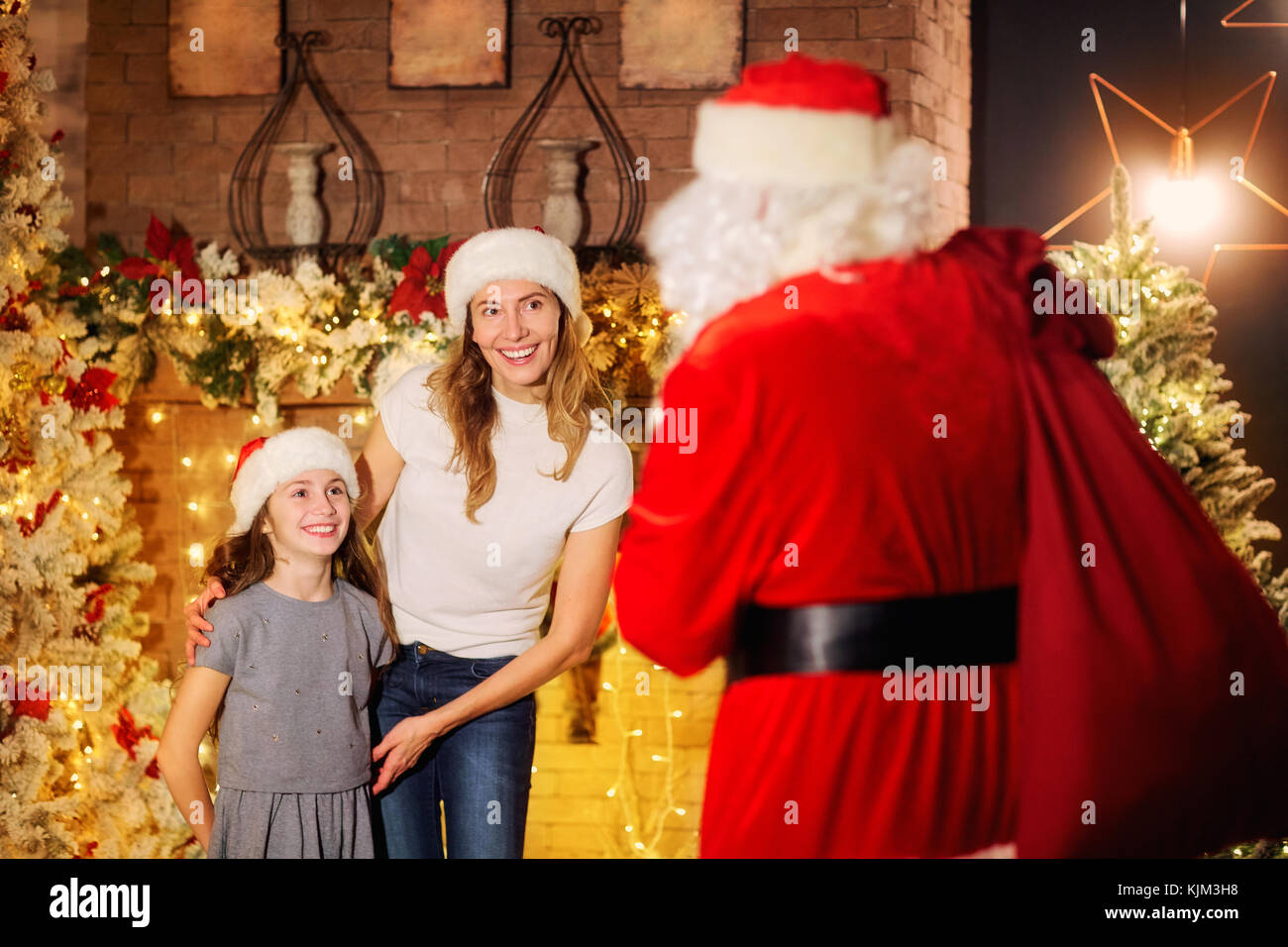 Santa Claus gibt ein Geschenk für ein Mädchen für Weihnachten im Zimmer. Stockfoto