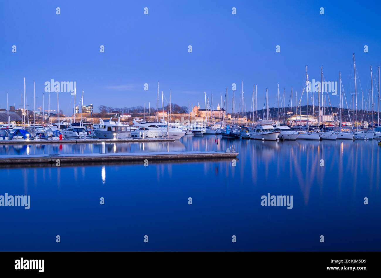 Winter Stimmung in Aker Brygge Marina, voller Schlaf Yachten, mit Burg Akershus, in ruhiger Abend. Oslo, Norwegen. Stockfoto