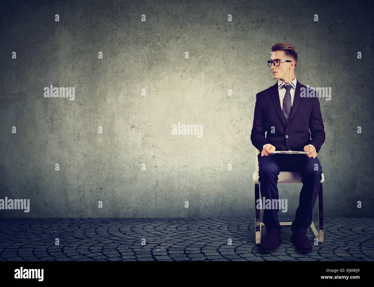 Junge Mann auf einem Stuhl sitzend warten auf Job Interview Stockfoto