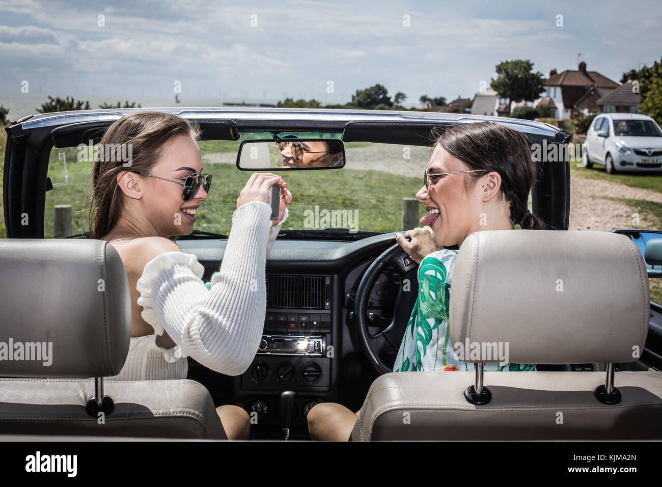 Zwei schöne junge Frauen auf einem Sommer Straße Reise zusammen in einem Cabrio. Stockfoto