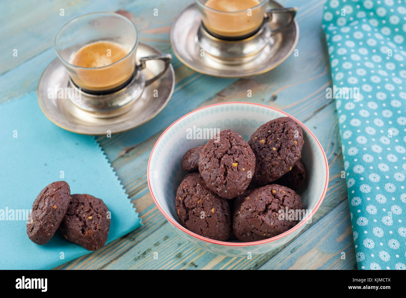 Rustikale Kekse mit Schokolade und Nüsse in Keramik Schüssel mit zwei Tassen Espresso und Stoffservietten Stockfoto